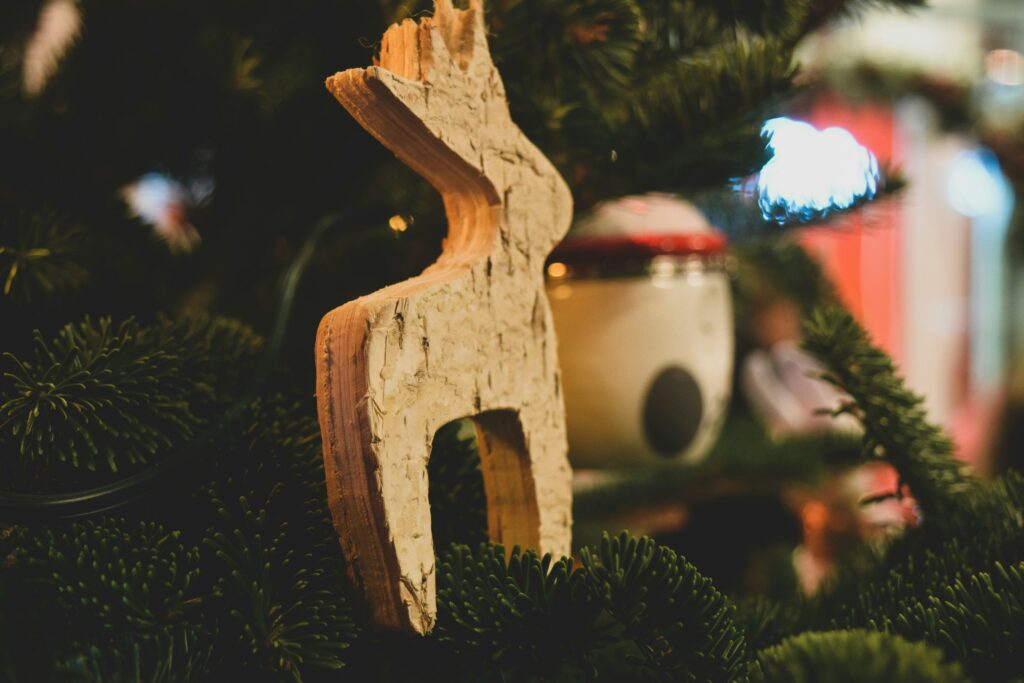 Wooden deer ornament hanging from Christmas tree.